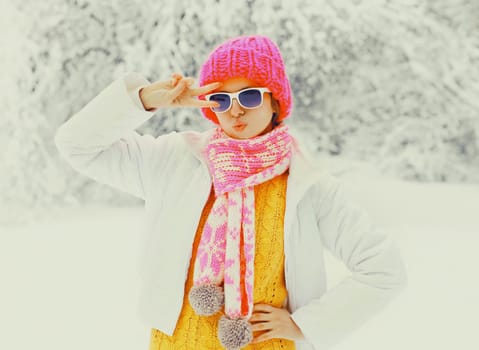 Fashion winter woman wearing a colorful knitted hat scarf having fun over snowy trees