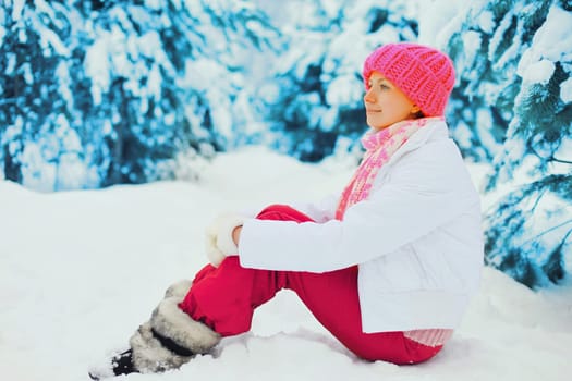 winter happy smiling woman sitting near branch christmas tree on snow in the park
