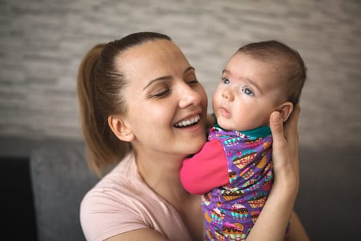 Caring mother holding newborn baby girl at home.