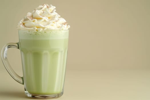 Green matcha latte with frothy foam in clear cup on light background with space for text, side view