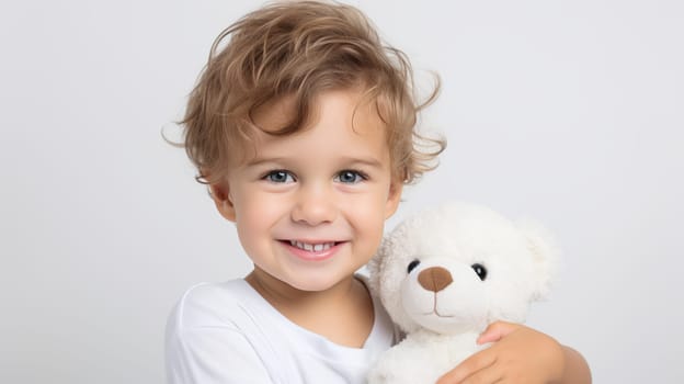 Smiling boy with prosthetic hand holding teddy bear in close up on white background