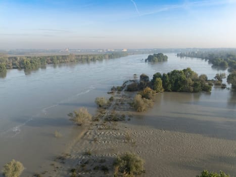 Stagno Lombardo, Italy - October 20th 2024 Aerial view of a river flooding the surrounding fields and forests after a heavy rain period, with the cloudy sky in the background