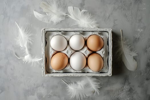 A carton holds six eggs of different colors, including white and light brown, placed on a textured gray surface. Soft feathers are scattered around, enhancing the tranquil atmosphere.