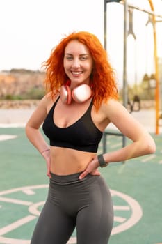 Happy sporty woman standing with hands on hip at outdoor gym. Portrait of smiling young female in sportswear is at park during daytime.