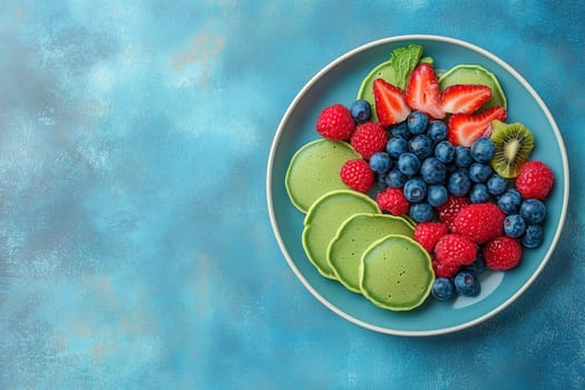 A colorful selection of fresh fruits including raspberries, blueberries, strawberries, and kiwi is artfully arranged alongside green pancakes, set against a blue background.