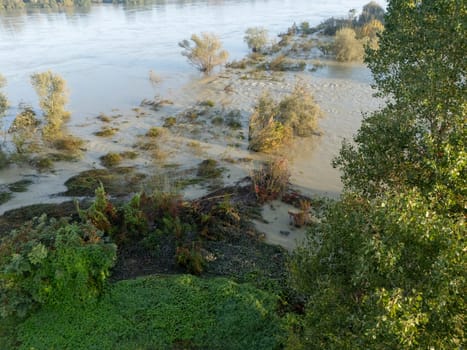 Stagno Lombardo, Italy - October 20th 2024 Aerial view of a river flooding the surrounding fields and forests after a heavy rain period, with the cloudy sky in the background