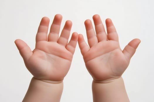A pair of small hands with open palms rests against a plain white background, symbolizing innocence and curiosity. The hands exhibit soft skin and gentle features, inviting interaction.