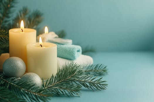 A tranquil winter setting features lit candles alongside soft towels and silver ornaments, all nestled among fresh pine branches on a serene blue background.