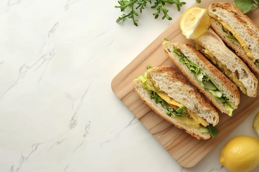 A wooden cutting board displays a freshly made sandwich filled with lettuce, tomato, and cheese, alongside bright lemon slices, conveying a vibrant meal idea.
