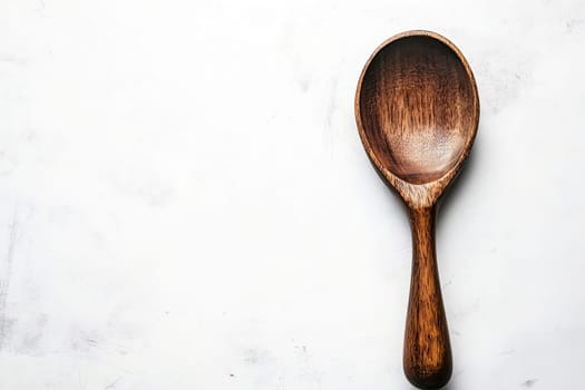 A wooden cooking spoon rests on a light textured surface, showcasing its organic shape and craftsmanship in a well-lit kitchen environment.