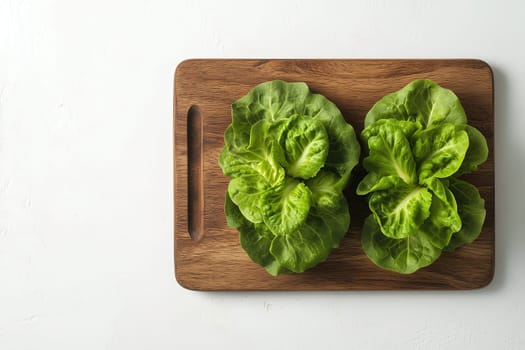 Two vibrant green lettuce heads are placed on a wooden cutting board, showcasing their crisp texture and lush leaves, ready for meal preparation.