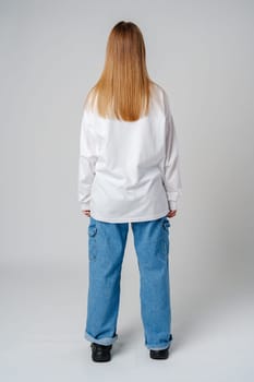 Young adult with long hair standing against a neutral background backwards in studio