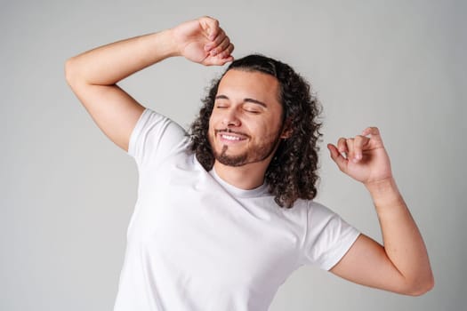Happy man celebrating success with raised fists in a studio against a plain background close up