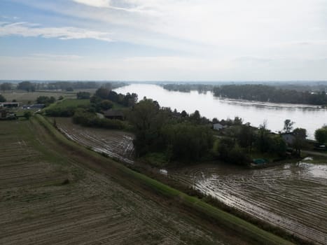 Stagno Lombardo, Italy - October 20th 2024 Aerial view of a river flooding the surrounding fields and forests after a heavy rain period, with the cloudy sky in the background