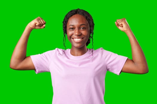 A young woman with braids expresses excitement with a clenched fist against a bright green background in studio