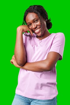 Happy young person laughing and playfully covering face while standing against a bright green background in studio