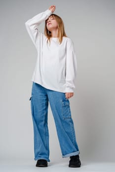 A young woman in a white long-sleeve shirt expressing a moment of contemplation against a neutral background close up