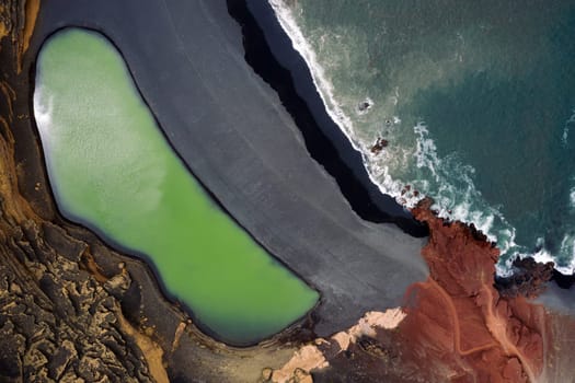 top view of Charco Verde against foamy ocean on a beach of black sand in Yaiza, Lanzarote at Canary Islands, Spain, Concept of wild nature and volcanic landscape