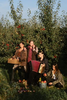 Four stylish girls have fun celebrating the apple harvest at sunset. Fashionable models at the fall apple harvest.