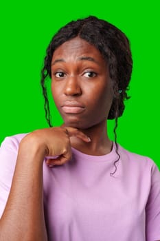 Thoughtful woman pondering in front of a bright green background during a casual moment close up