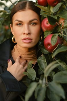 Close-up of a girl's face in an apple orchard. A fashionable girl on the background of a tree with red apples.