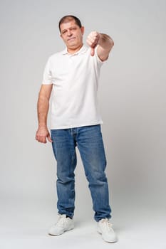 A middle-aged man expressing disapproval with a thumbs-down gesture in a neutral setting