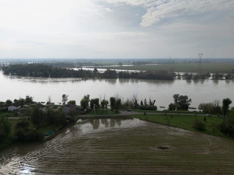 Stagno Lombardo, Italy - October 20th 2024 Aerial view of a river flooding the surrounding fields and forests after a heavy rain period, with the cloudy sky in the background