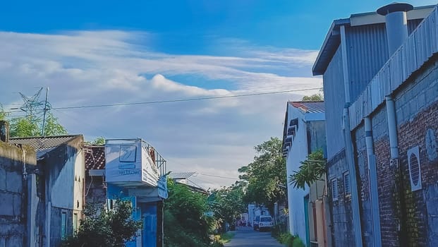 A road in the middle of village. Colorful buildings. Blue sky filled with clouds