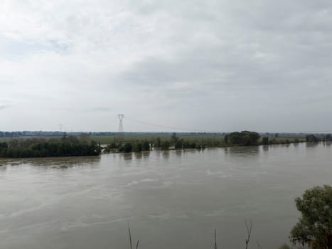 Stagno Lombardo, Italy - October 20th 2024 Aerial view of a river flooding the surrounding fields and forests after a heavy rain period, with the cloudy sky in the background