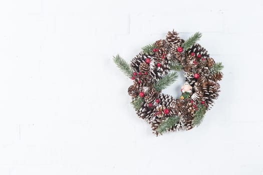 Elegant christmas wreath decorated pine cones and fir trees on white light grey wooden door. Christmas mood. Beautiful vintage door. Christmas mood: festive christmasy themed winter natural wreath on