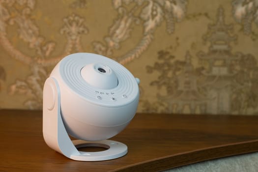 Home space projector stands on shelf in room, device for studying planets and stars, realistic space projector for learning at home