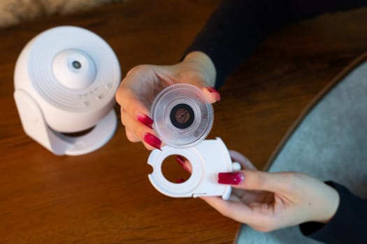 Installing film disc in cartridge for galactic starry sky projector on the ceiling of room for exploring deep space, home planetarium using compact device for room