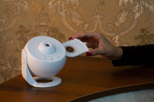 Installing cartridge with galaxy image into special device for projecting the starry sky onto the ceiling of room, home planetarium using compact device for space exploration