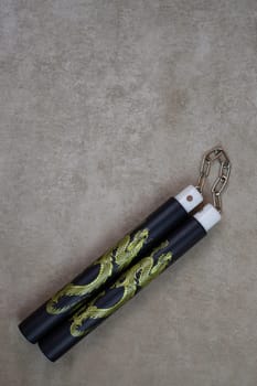 Vertical photography of training nunchucks for self training in use of melee weapons on light background, traditional oriental edged weapons of impact and strangulation type