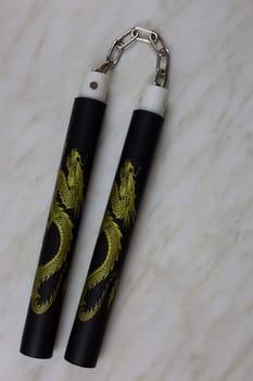 Eastern melee weapons, training nunchucks for learning strikes and improving body dexterity at home, unusual edged weapons on a white table, vertical photo