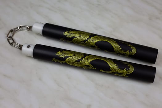 Training nunchucks made of soft material on white background, oriental inertial edged weapons of impact, shock-crushing and suffocating action, foam rubber training nunchucks