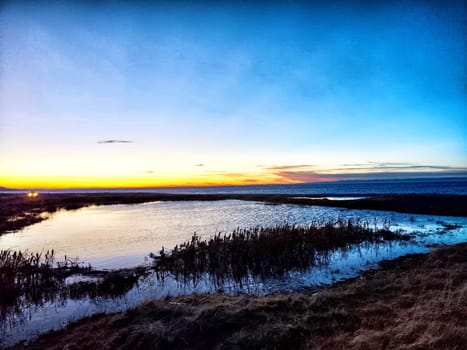 A stunning sunset paints the sky in vibrant colors while water reflects the serene beauty of the evening landscape.