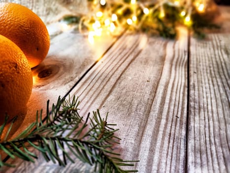 Festive decoration with bouquet and branches of spruce, bright glowing garland, orange, burlap on wooden background. Decor for Christmas, New Year. Abstract texture, frame, place for text, copy space