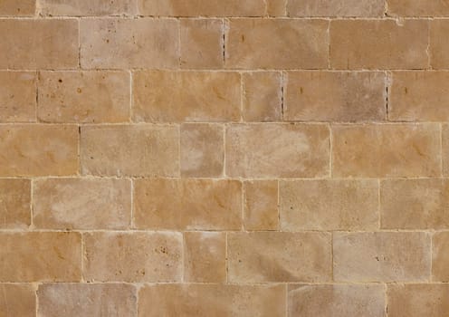 A detailed view of a seamless stone wall texture, showcasing its natural beige tones and subtle color variations. The rough surface provides a consistent, rustic background suitable for architectural use.