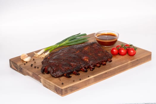 Succulent barbecue ribs, beautifully garnished with fresh scallions, vibrant cherry tomatoes, and a rich dipping sauce