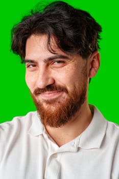 A man with a beard smiles confidently against a bright green background close up