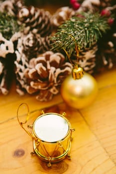 Small gold drum ornament and a gift box with a shiny, metallic wrapping placed on a wooden surface. The festive decorations capture the essence of Christmas and New Year celebrations, creating a warm and joyful holiday atmosphere.