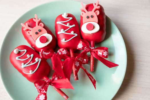 Flat lay of cake pops ice cream on a stick in pink glaze with strawberries and blueberries on a light background.