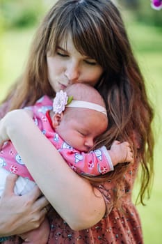 Mother cradles her sleeping baby girl in the warm sunlight outdoors. Sharing a serene moment in nature. The bond between them is evident. Capturing the innocence and joy of motherhood and childhood