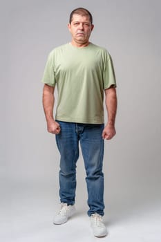 Man in casual attire standing posed against a neutral background, displaying a serious expression close up