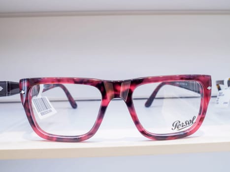 Pair of pink tortoise shell designer eyeglasses sits on a white shelf, ready to help a customer see more clearly