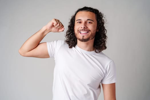 Happy man celebrating success with raised fists in a studio against a plain background close up