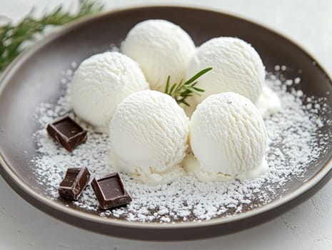 A plate features several scoops of creamy vanilla ice cream, garnished with chocolate pieces and a dusting of powdered sugar, inviting indulgence at dessert time.