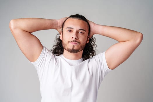 Young man with curly hair poses confidently against a plain background close up