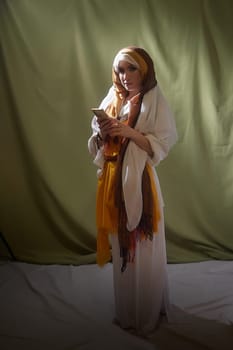 Dressed in stylized national clothing, the girl holds a phone while embodying Rebekah's character, evoking cultural and biblical themes.